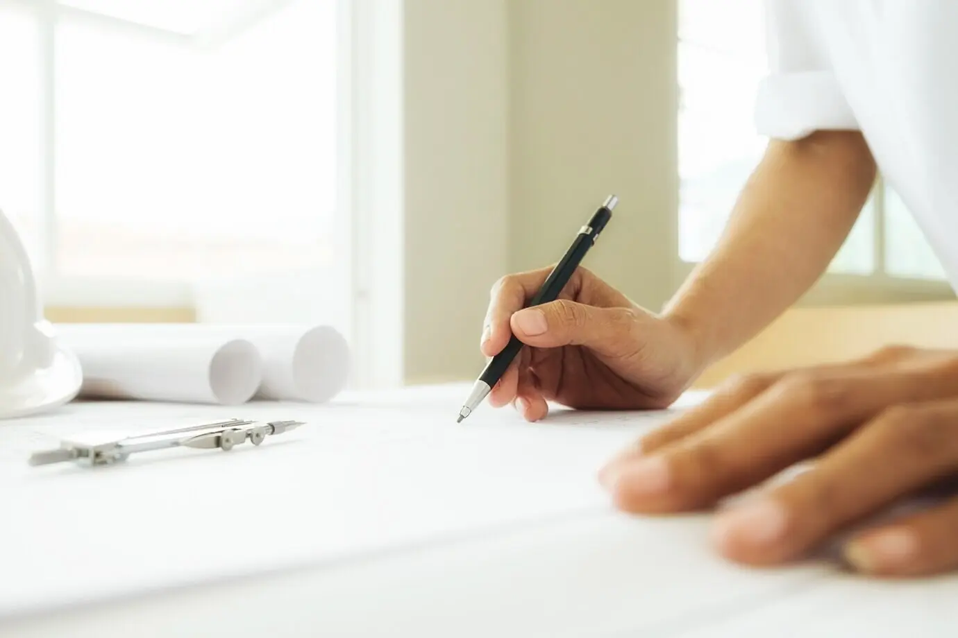 Hände eines Ingenieurs, der an einem Bauplan arbeitet; Baukonzept. Ingenieurwerkzeuge. Vintage-Ton mit Retro-Filtereffekt, weicher Fokus (selektiver Fokus).